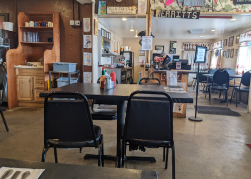 A cozy diner interior with empty black tables and chairs, condiments on the table, and a welcoming atmosphere.