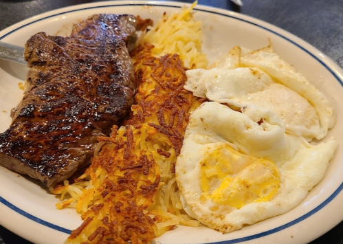 A plate featuring a grilled steak, crispy hash browns, and two sunny-side-up eggs.