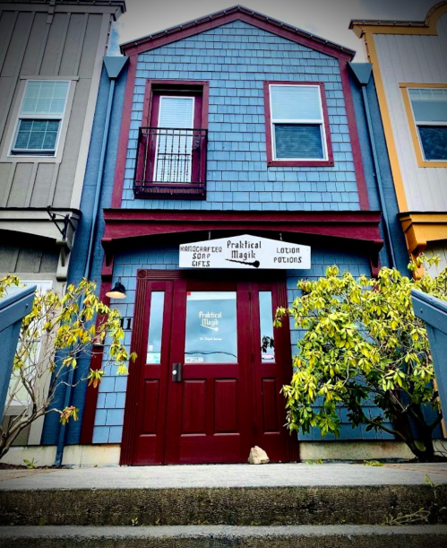 A colorful building with a red door and sign for "Practical Magic" offering handcrafted gifts and lotion potions.