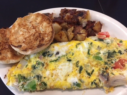 A plate with a vegetable omelette, crispy potatoes, and toasted English muffins.