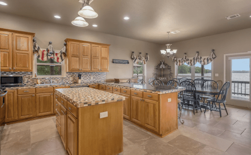 Bright kitchen with wooden cabinets, tiled countertops, and a dining area overlooking a scenic view.