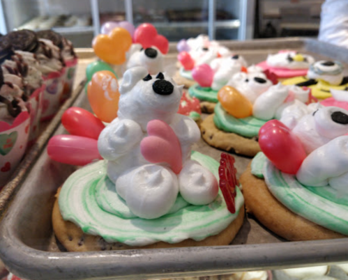 Colorful cookies topped with polar bear decorations, balloons, and frosting on a tray.