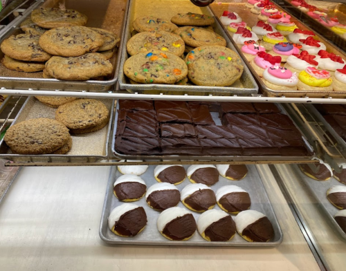 A display of assorted baked goods, including cookies, frosted donuts, and chocolate-covered treats.