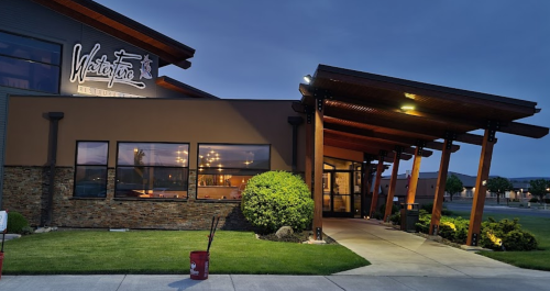 Exterior of Waterstone restaurant at dusk, featuring a modern design with wooden accents and landscaped entrance.