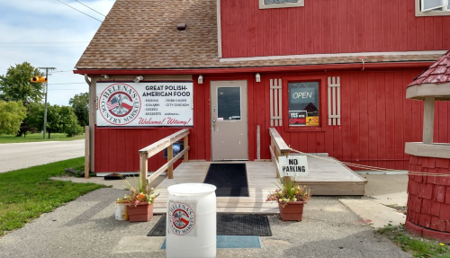 Exterior of a red restaurant with a sign for Polish and American food, featuring a ramp and "No Parking" sign.