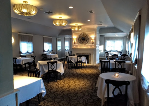 Elegant restaurant interior with white tablecloths, soft lighting, and a cozy fireplace.