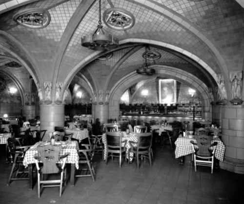 A vintage restaurant interior featuring arched ceilings, checkered tablecloths, and wooden chairs.