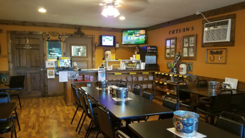 Interior of a casual dining restaurant with wooden decor, tables, and a counter displaying drinks and snacks.