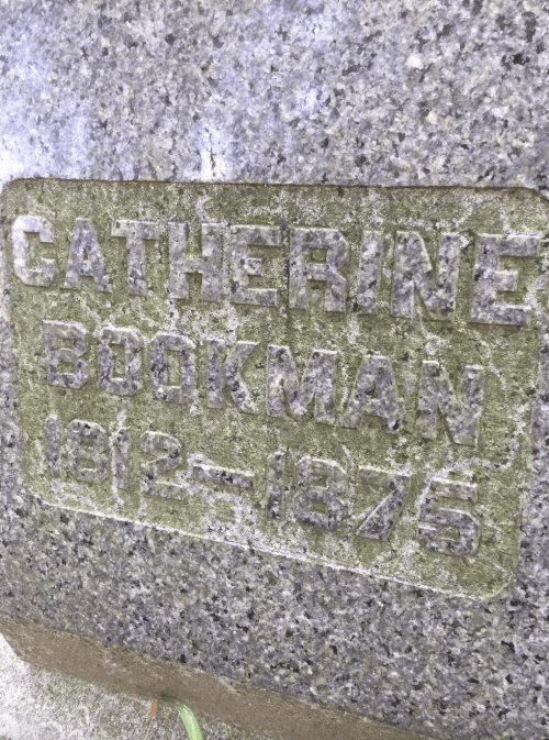 Gravestone inscription reading "Catherine Bookman 1912-1976" on a textured stone surface.
