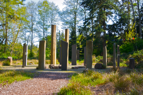 A circle of tall stone pillars surrounded by trees and greenery in a serene outdoor setting.