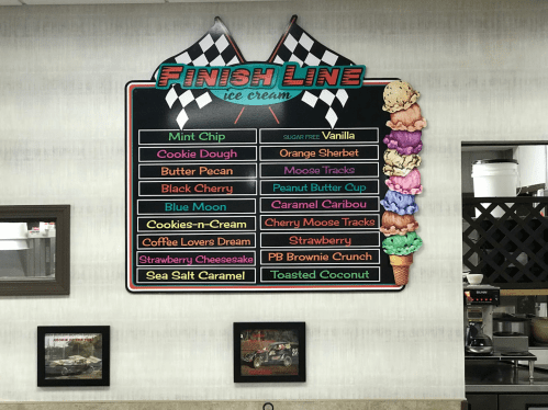 Menu board for "Finish Line Ice Cream" featuring various ice cream flavors like Mint Chip, Cookie Dough, and Sea Salt Caramel.