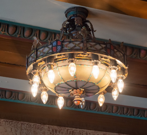 A decorative chandelier with multiple light bulbs, featuring intricate metalwork and colorful accents.