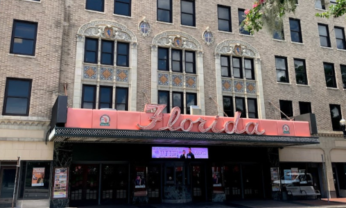 Historic Florida Theater facade with ornate details and a pink marquee, surrounded by large windows.