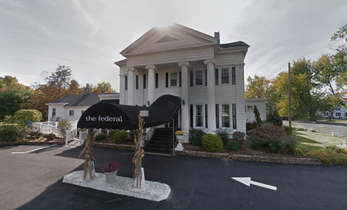 A historic white building with columns, featuring a black awning labeled "the federal" and autumn foliage around it.