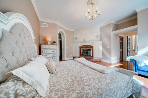 Spacious bedroom with a large bed, elegant decor, a fireplace, and a cozy seating area.