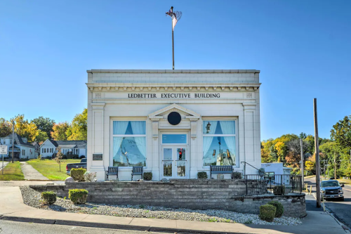 Historic Ledbetter Executive Building with blue curtains, surrounded by greenery and a clear blue sky.