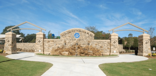 Entrance to Elizabeth Porter Park, featuring a stone wall and decorative archways under a clear blue sky.