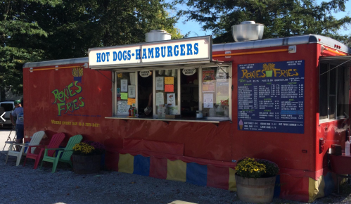A colorful food truck named "Roxie's Fries" serving hot dogs and hamburgers, with a menu displayed on the side.