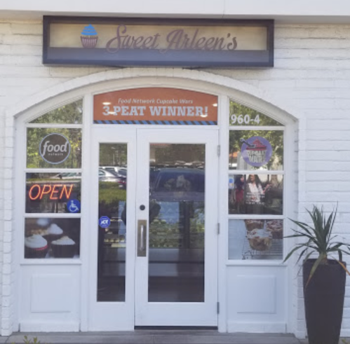 Exterior of Sweet Arleen's bakery with a sign announcing it as a "3-Peat Winner" on Food Network's Cupcake Wars.