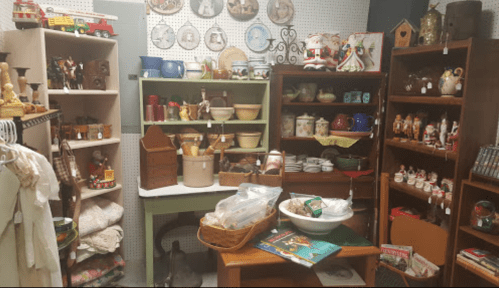 A cozy vintage shop filled with shelves of collectibles, dishes, and home decor items.