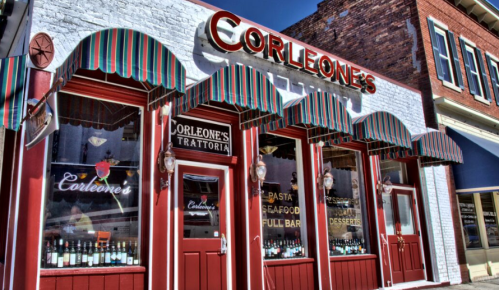 Exterior of Corleone's Trattoria, featuring colorful awnings and large windows showcasing the restaurant's offerings.