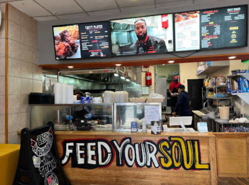 A restaurant counter with a menu display, staff, and a sign that says "FEED YOUR SOUL."