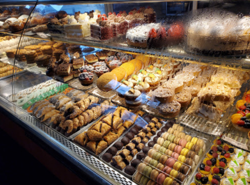 A display case filled with a variety of colorful pastries, cakes, and desserts, all beautifully arranged.