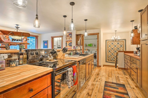 Modern kitchen with wooden countertops, stainless steel appliances, pendant lighting, and a cozy, inviting atmosphere.