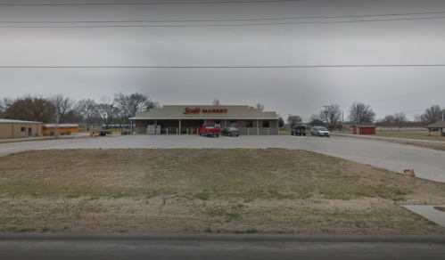 A storefront of Snob Market with a parking lot, surrounded by trees and a cloudy sky.