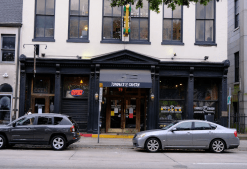 Exterior of Tondee's Tavern, featuring large windows, an "Open" sign, and parked cars in front.