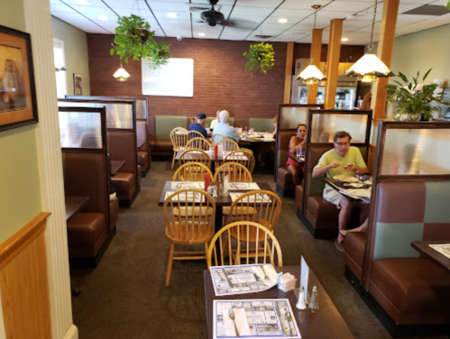 A cozy restaurant interior with wooden booths, tables, and diners enjoying their meals in a relaxed atmosphere.