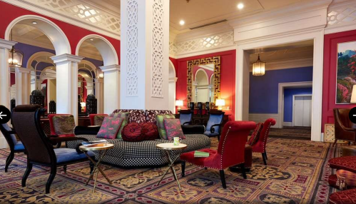 Elegant lounge with colorful walls, ornate arches, plush seating, and decorative rugs, creating a cozy atmosphere.
