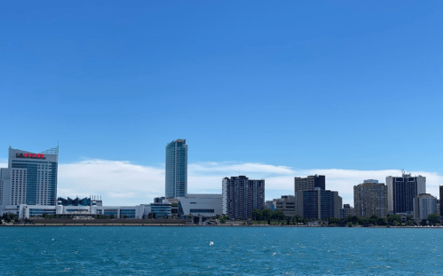 City skyline with modern buildings along the waterfront under a clear blue sky.