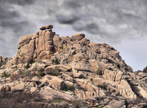 A rugged rock formation with large boulders under a cloudy sky, showcasing natural textures and shapes.