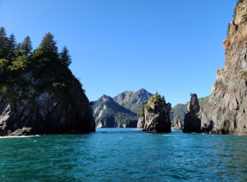 A serene coastal scene featuring rocky cliffs and clear blue water under a bright blue sky.