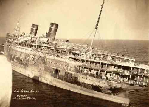 Black and white photo of the S.S. Morro Castle, a ship listing in the ocean, showing signs of damage and decay.