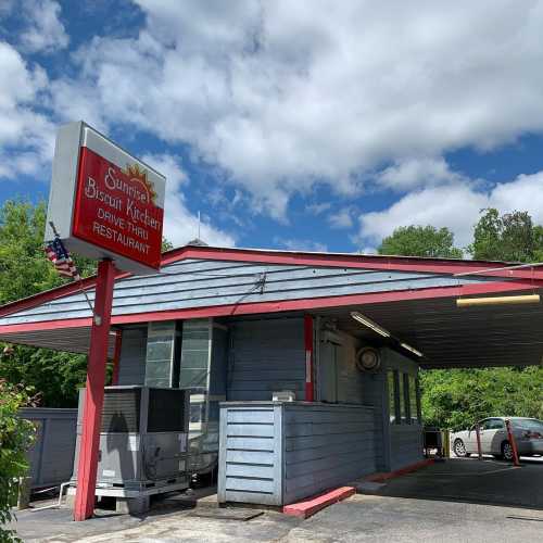 Exterior of Sunrise Biscuit Kitchen, a drive-thru restaurant, with a sign and blue sky in the background.