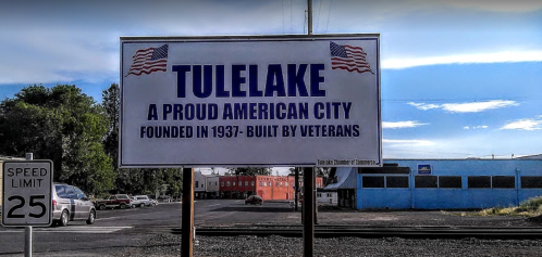 Sign for Tulelake, stating it’s a proud American city founded in 1937 and built by veterans. Speed limit sign nearby.