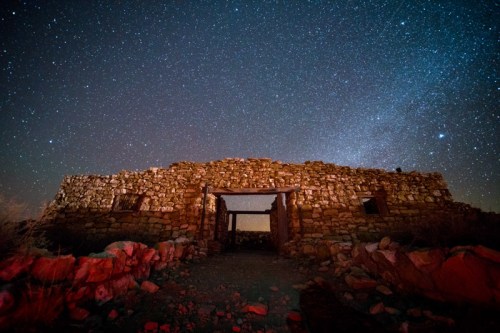 A stone ruin under a starry night sky, with a clear view of stars and a hint of the Milky Way in the background.