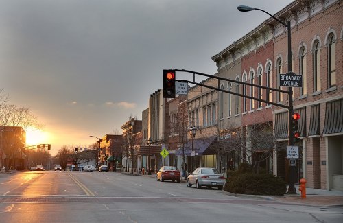 A quiet street at sunset, featuring shops along Broadway Avenue and traffic lights signaling red.