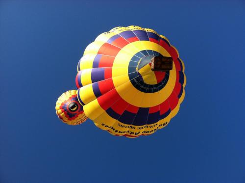 Two colorful hot air balloons in a clear blue sky, one larger and one smaller, with vibrant patterns.