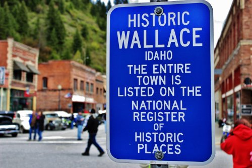 Blue sign reading "Historic Wallace, Idaho" with text about the town's listing on the National Register of Historic Places.