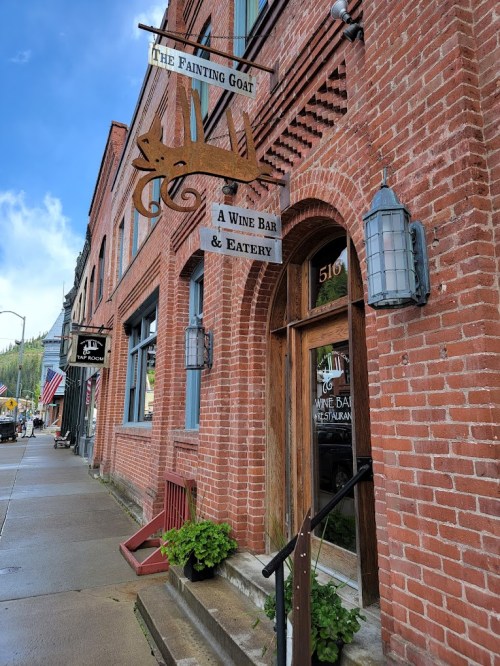 Exterior of "The Fainting Goat," a wine bar and eatery, featuring a brick facade and a wooden sign.