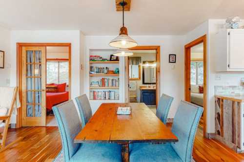 A cozy dining area with a wooden table, blue chairs, and bookshelves in a bright, inviting space.