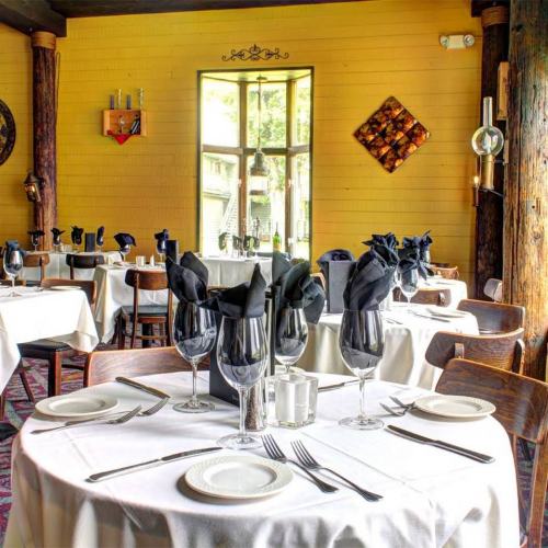 Elegant restaurant interior with neatly set tables, black napkins, and warm yellow walls.