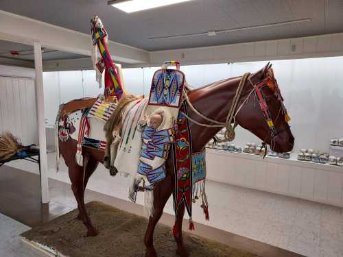 A decorated horse model with colorful traditional attire displayed in a museum setting.