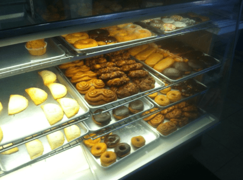 A display case filled with various pastries, including donuts, cookies, and sweet rolls.