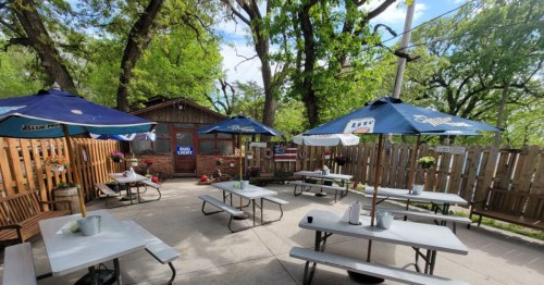 exterior patio under the trees with picnic tables and umbrellas at alpine inn omaha nebraska