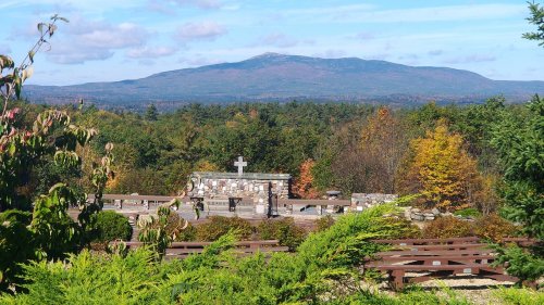 A scenic view of a mountain in the background, framed by colorful trees and a stone monument in the foreground.