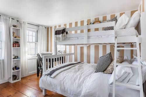 Cozy bedroom with a bunk bed, a double bed, striped walls, and natural light from a window.